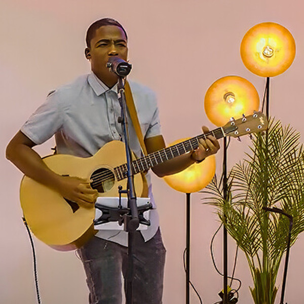 Jervis Djokoto, a local musician and worship leader in Toronto, Canada, plays guitar and sings into a microphone