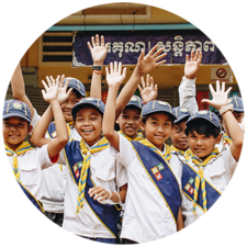 A group of children from an elementary school in Cambodia wave and smile