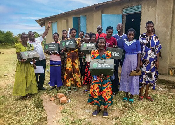group of happy people holding safe boxes with Food for the Hungry logo on it