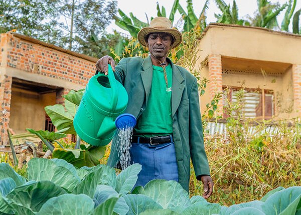 men with a hat watering his plants