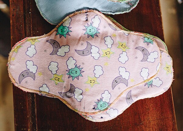 fabric sanitary pads in pink with moons, stars, clouds and suns as pattern