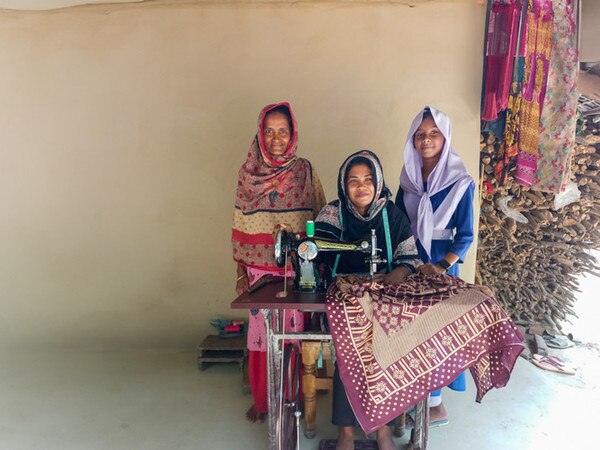 three woman in front of a sewing machine