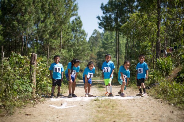 group of children with numbers on their tshirts behind a white line on the floor ready to run 