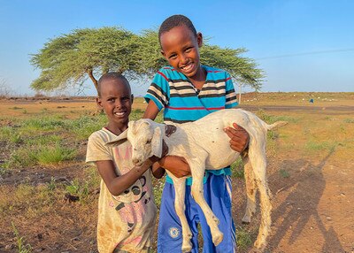 two happy boys holding a goat