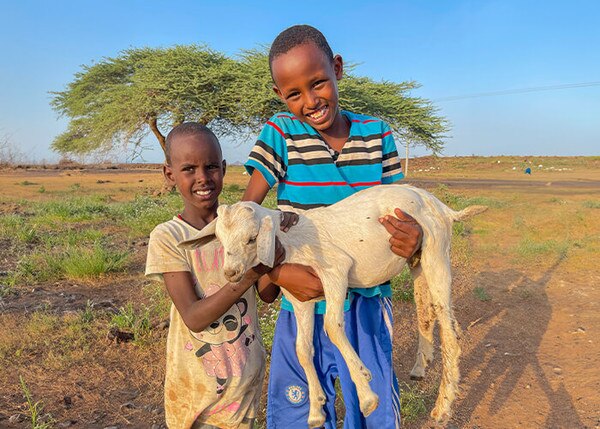 two happy boys holding a goat
